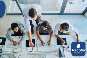 Équipe de professionnels en open space travaillant sur ordinateurs, représentant la gestion amiable et collaborative des factures impayées dans un cadre moderne et sérieux.
